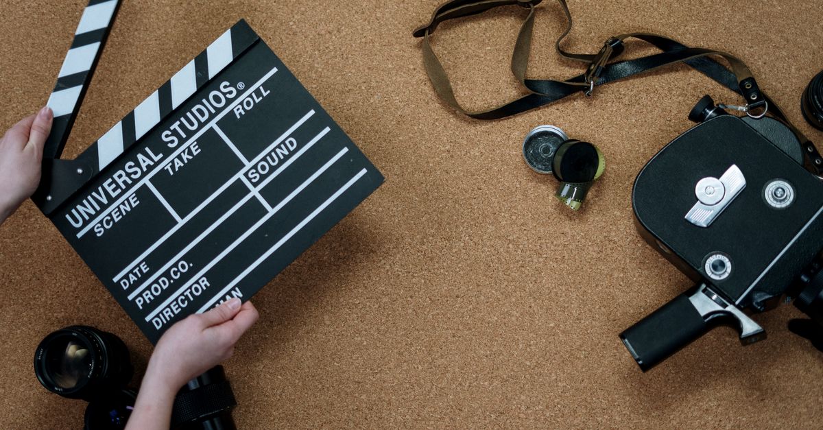 Top view of vintage film camera and clapperboard on cork background, evoking old cinema vibes.